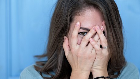 Frau mit Erythrophobie versteckt sich hinter ihren Händen - Foto: iStock/Koldunov