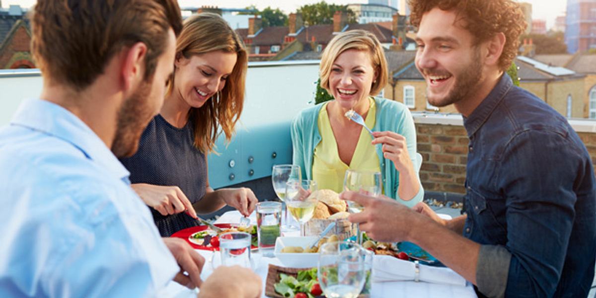 Freunde beim gemeinsamen Abendessen auf einer Dachterrasse