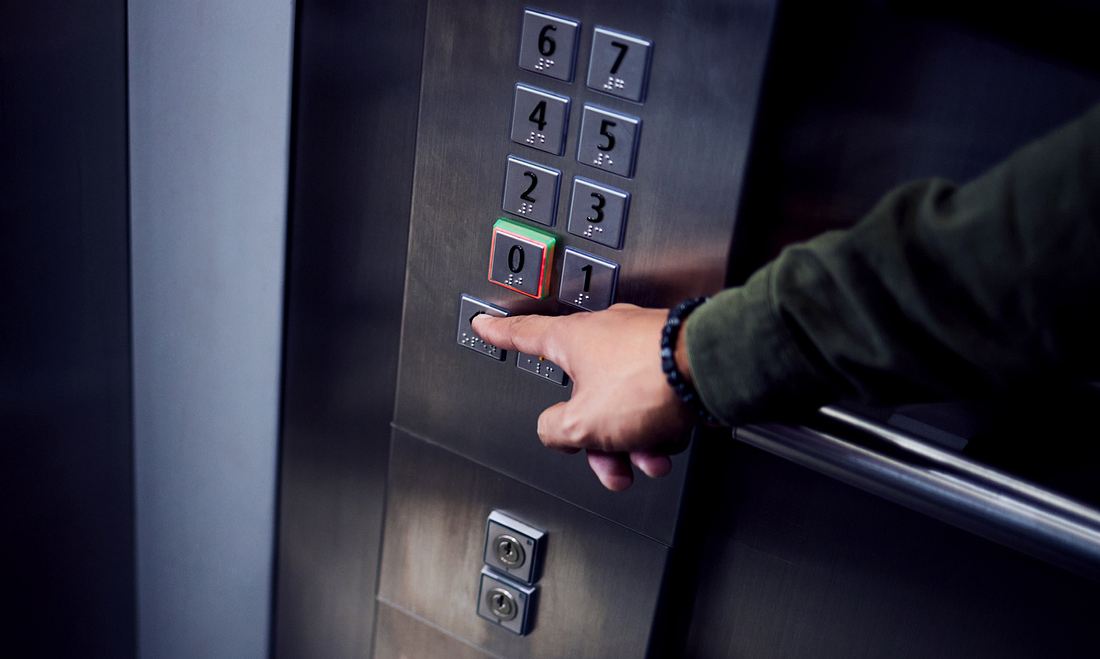 Person drückt im Fahrstuhl auf Knopf