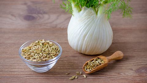 Fenchel sowie eine Schale und ein Holzlöffel mit Fenchelsamen auf einem Holztisch - Foto: istock_nadisja