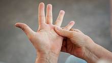 Eine Person massiert ihre Finger und Handfläche. - Foto:  iStock / Mindful Media 