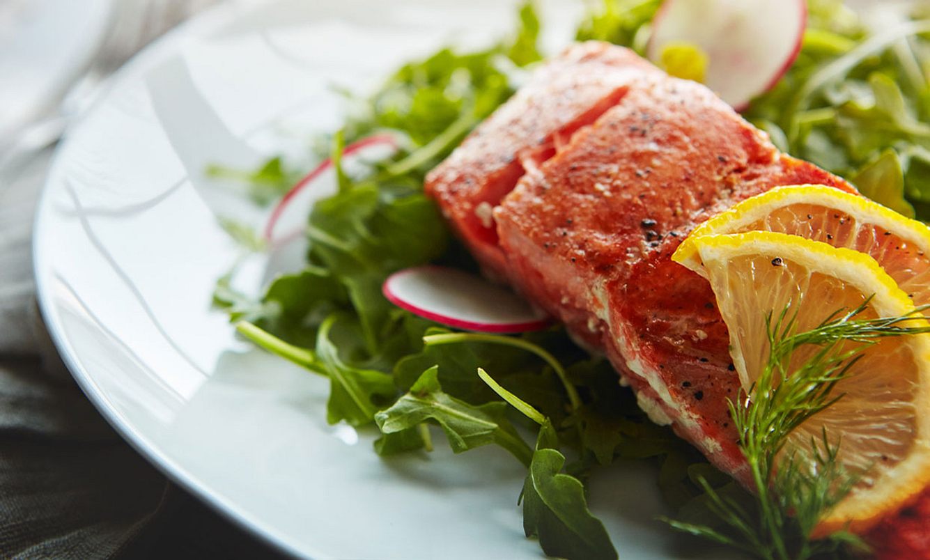 Fisch mit Zitrone und Salat auf einem Teller