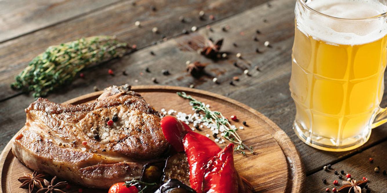 Stück Fleisch auf einem Teller und Bierglas