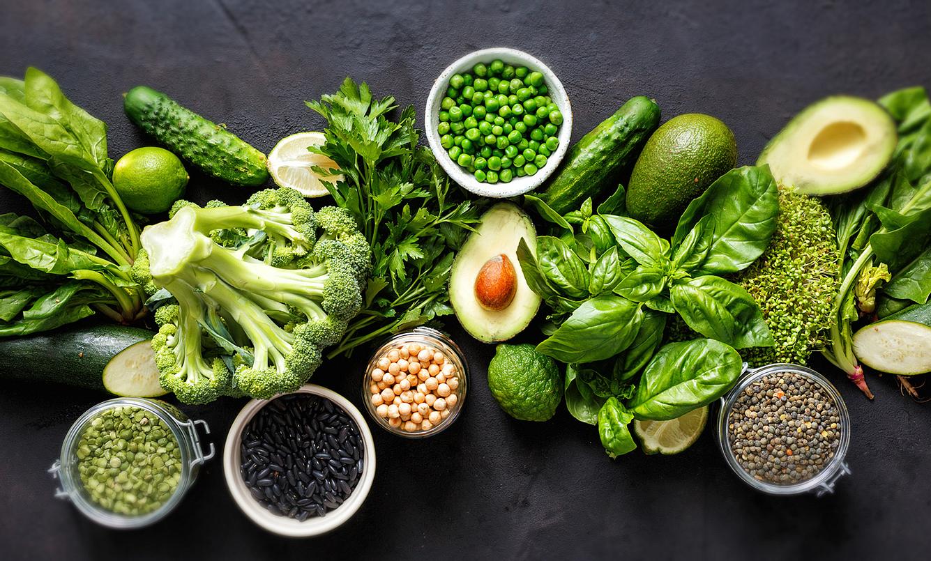 Spinat, Broccoli, Erbsen und andere Lebensmittel auf dunklem Untergrund