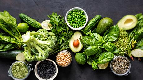 Spinat, Broccoli, Erbsen und andere Lebensmittel auf dunklem Untergrund - Foto: iStock-1051702322 KucherAV