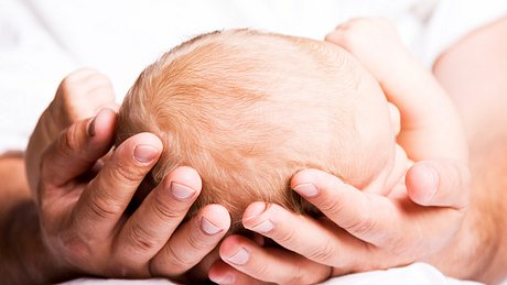 Baby liegt in Händen - Foto: iStock/Lloret