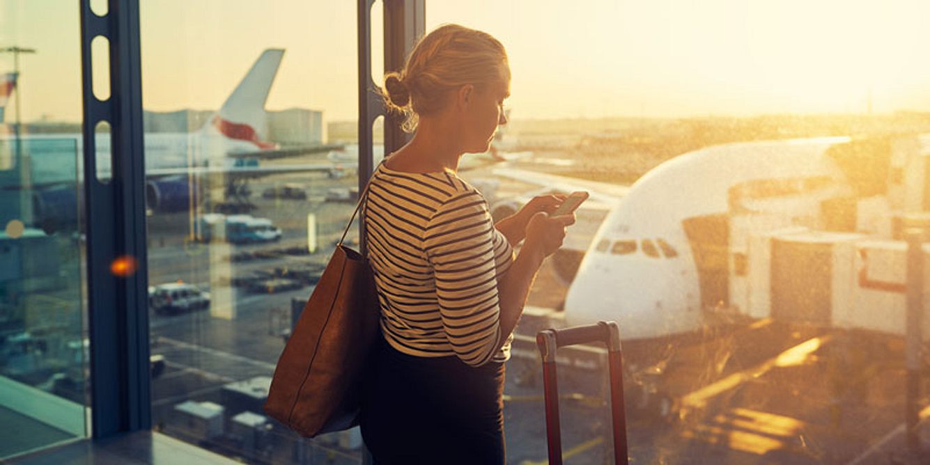 Frau am Flughafen guckt aus dem Fenster