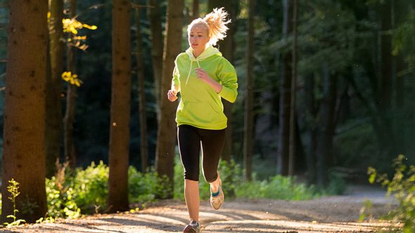 Eine Frau joggt im Wald - Foto: Fotolia