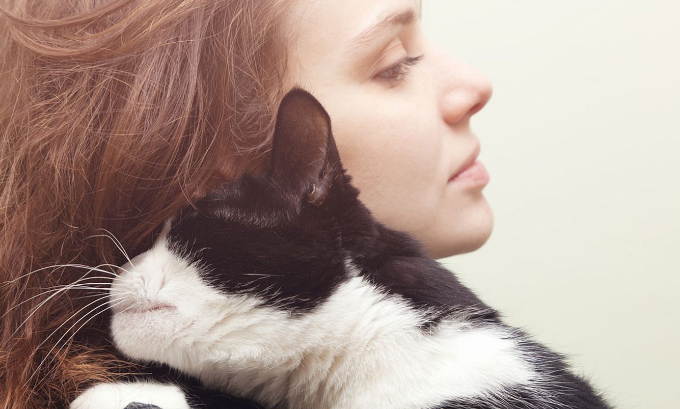 Frau hat schwarz weiße Katze auf dem Arm