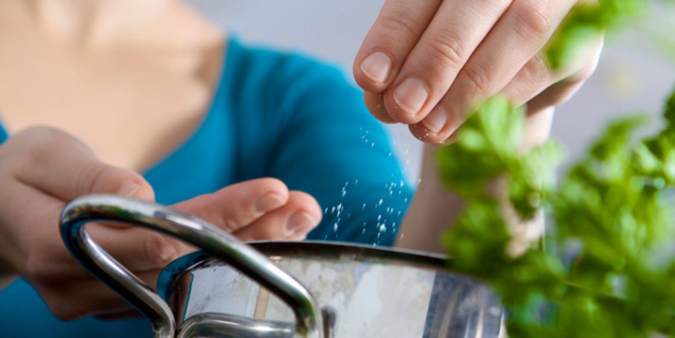 Eine Frau schüttet Salz in einen Topf