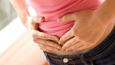 Eine Frau hält sich den Bauch - Foto: Alamy