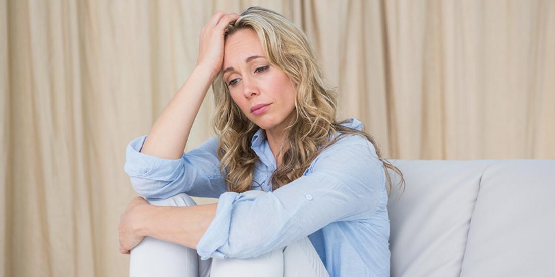 Frau mit depressiver Verstimmung sitzt auf dem Sofa