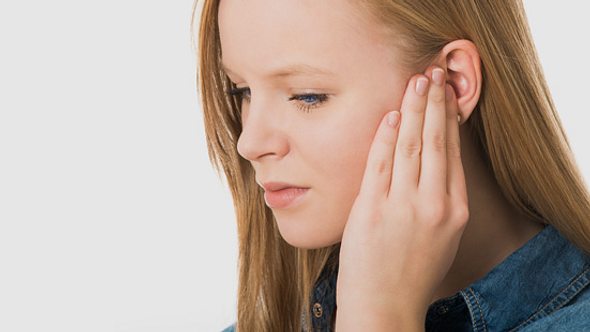 Eine Frau hält sich ihr Ohr - Foto: Shutterstock