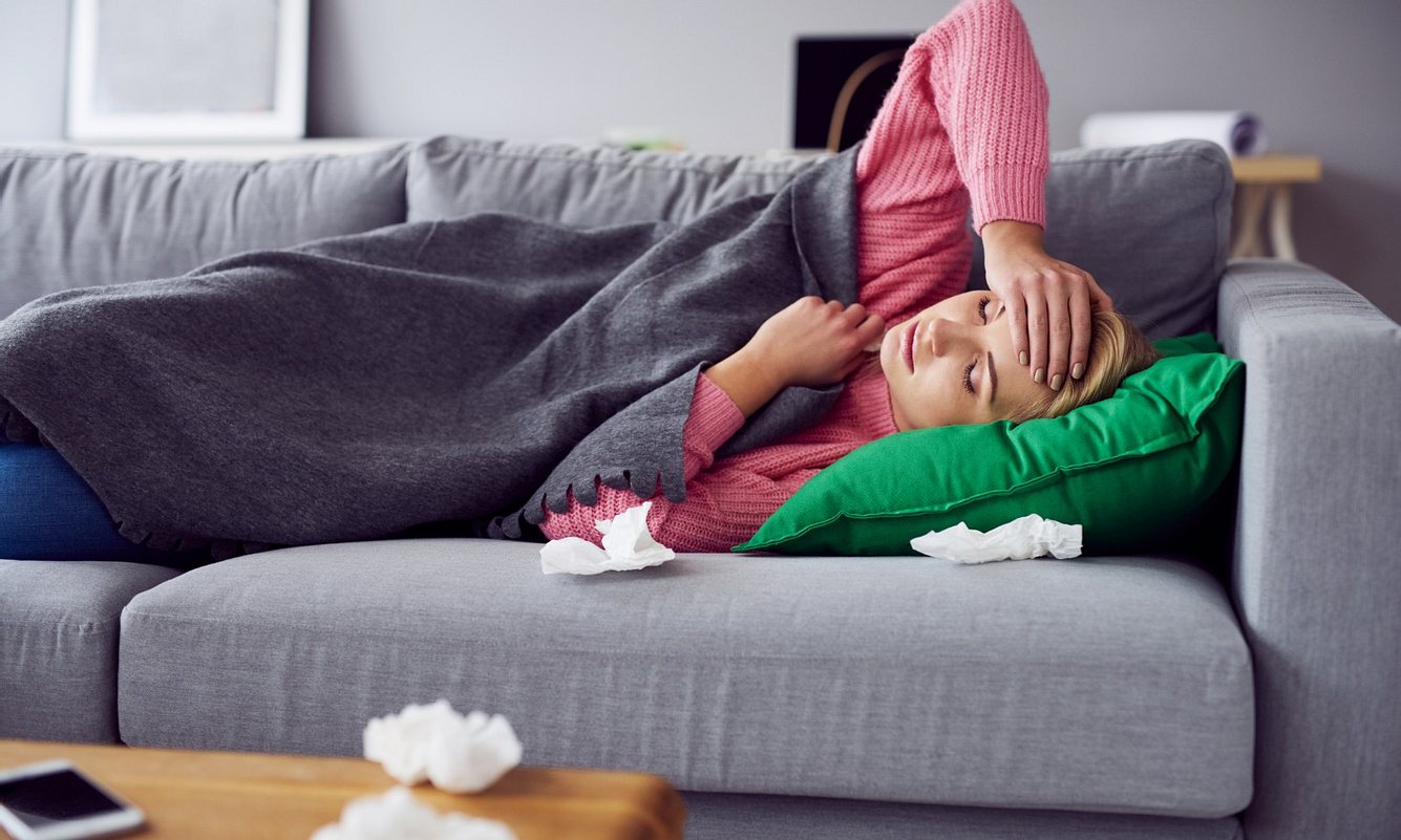 Frau mit Typhus im Anfangsstadium liegt auf dem Sofa