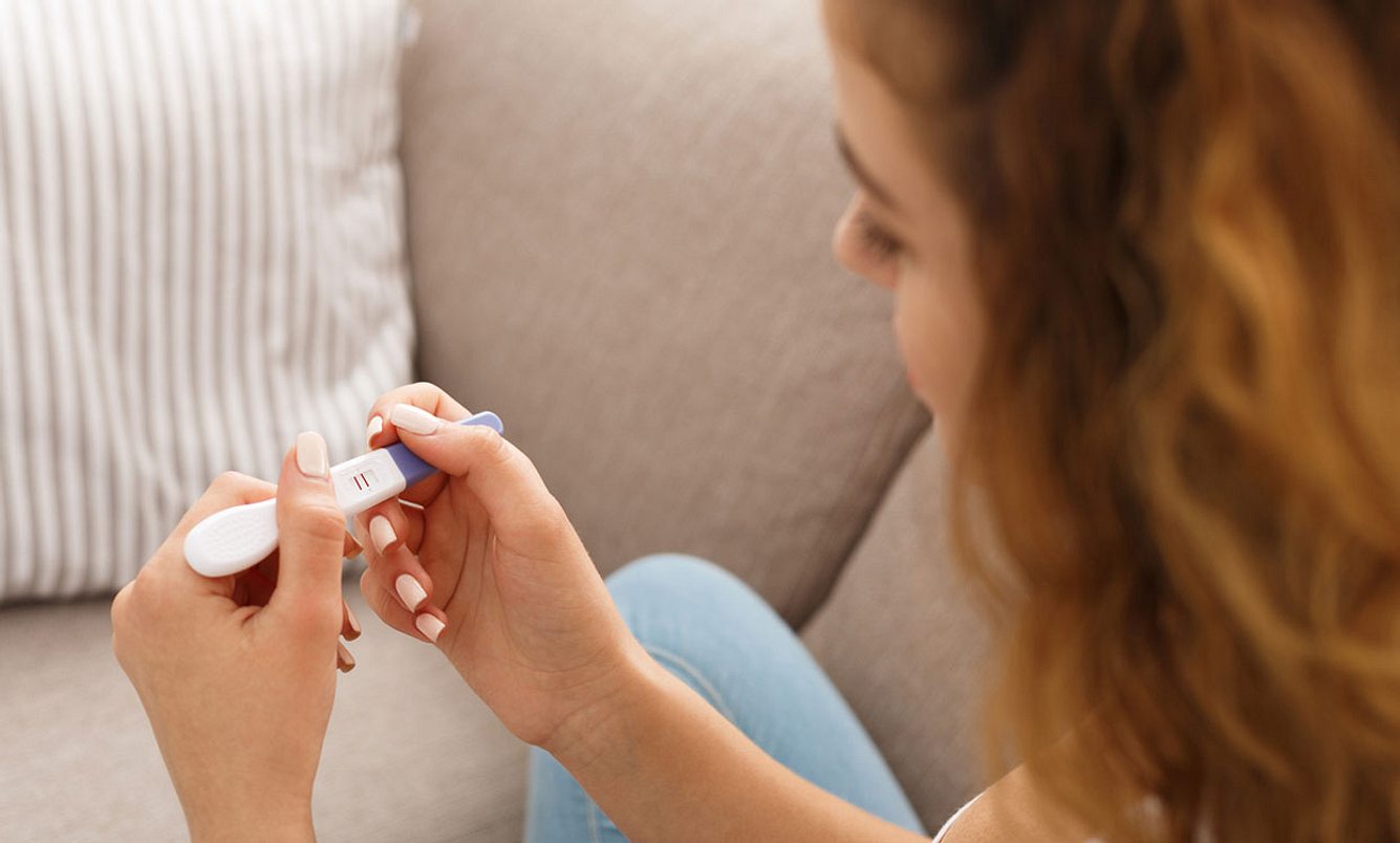 Junge Frau hält Schwangerschaftstest in der Hand