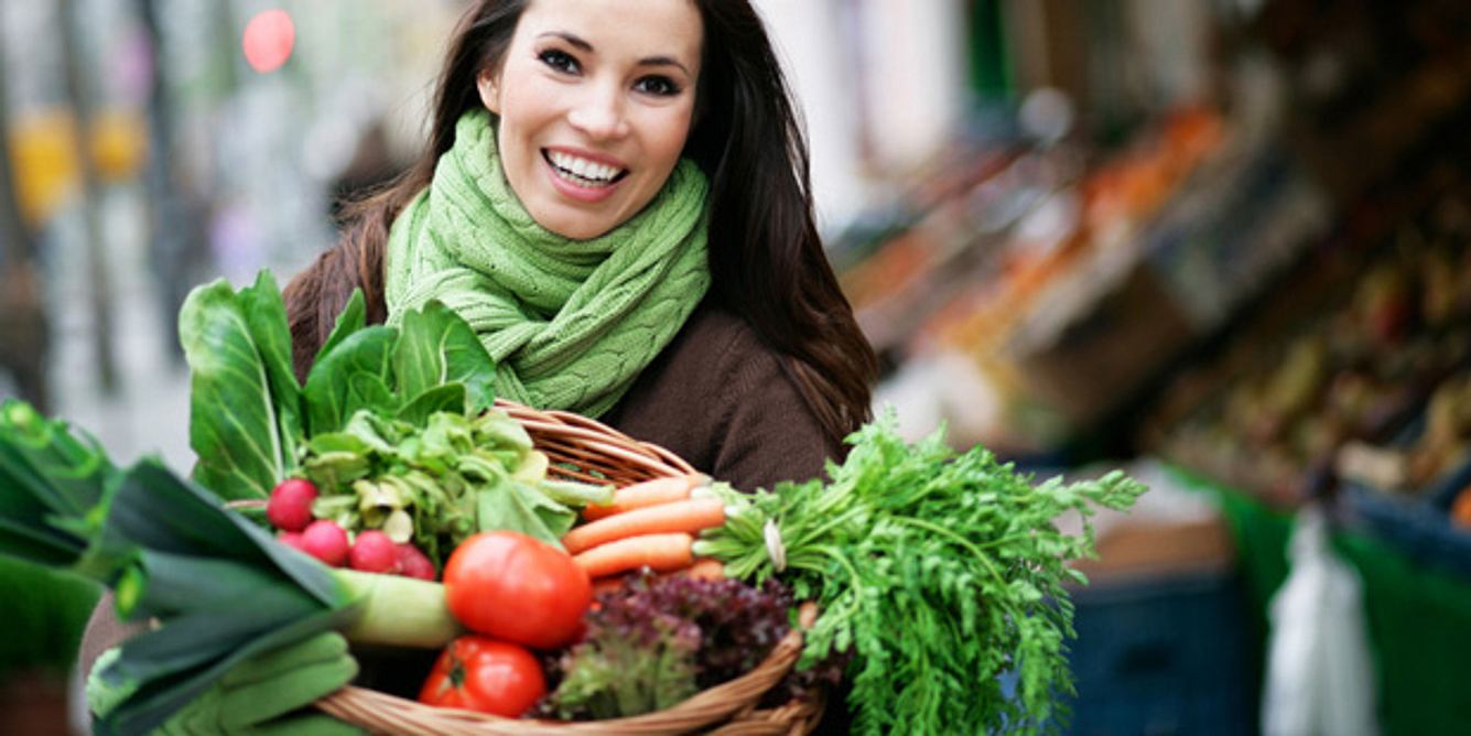 Eine Frau trägt einen Korb mit Gemüse