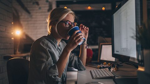 Eine Frau trinkt abends Kaffee am Computer - Foto: AleksandarNakic/iStock
