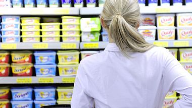 Eine Frau steht vor einem Supermarktregal und denkt nach - Foto: Fotolia