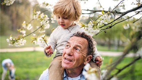 Ein älterer Mann trägt ein kleines Kind auf seinen Schultern - Foto: istock_Halfpoint