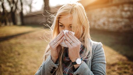 Frau mit Frühblüher-Allergie putzt sich die Nase mit einem Taschentuch - Foto: iStock/bojanstory