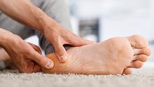 Eine Person massiert die Ferse ihres rechten Fußes.  - Foto: iStock / Dima Berlin