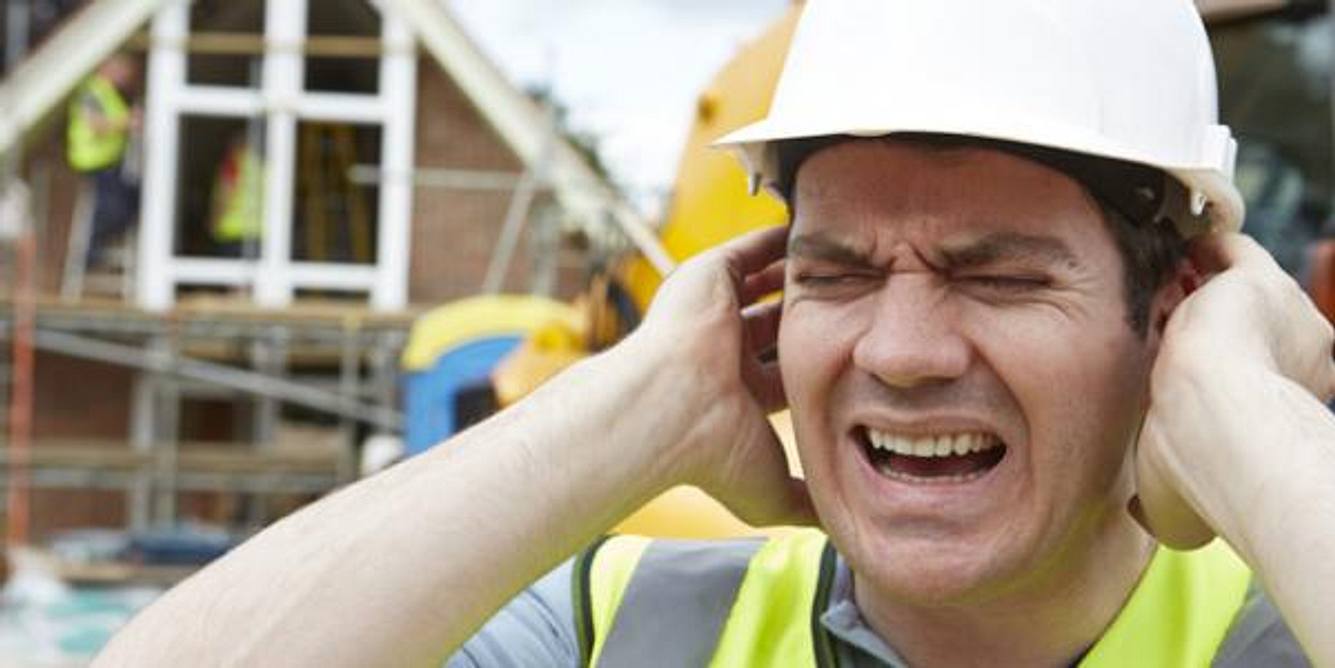 Ein Bauarbeiter hält sich die Ohren zu