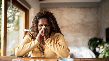 Eine erkältete Frau putzt sich ihre Nase - Foto: iStock_FG Trade