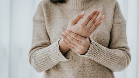 Eine Frau fasst sich ans Gelenk - Foto: iStock_interstid