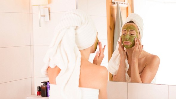 Frau mit Gesichtspeeling vor einem Spiegel - Foto: istock/artursfoto