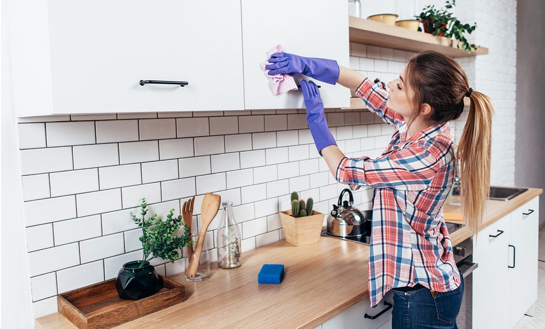 Eine Frau wischt einen Küchenschrank ab