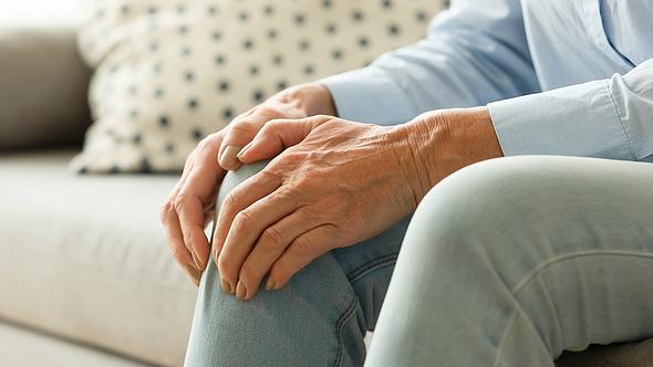 Eine ältere Frau hält sich ihr Knie - Foto: iStock/fizkes