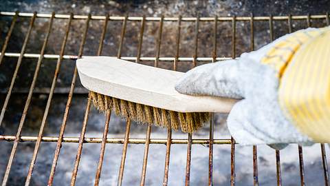 Ein Grillrost aus Edelstahl wird mit einer Bürste gesäubert. - Foto: iStock/In Stock