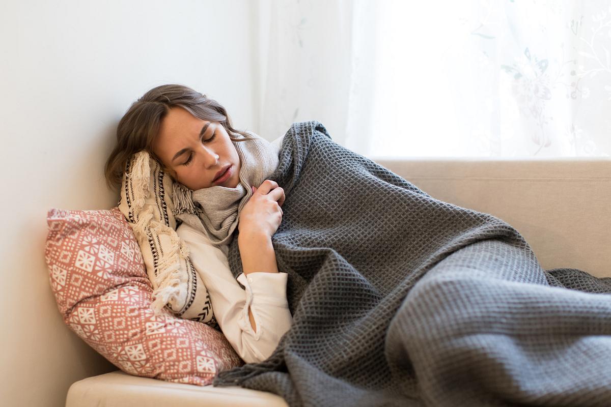 Grippekranke Frau liegt auf dem Sofa