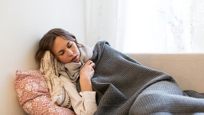 Grippekranke Frau liegt auf dem Sofa - Foto: iStock/Dima Berlin