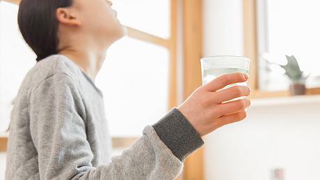 Frau hält Glas in der Hand und gurgelt - Foto: istock/okugawa