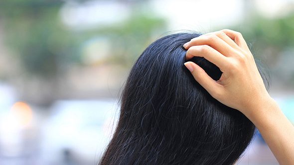 Eine dunkelhaarige Frau fasst sich in die Haare - Foto: iStock/MonthiraYodtiwong