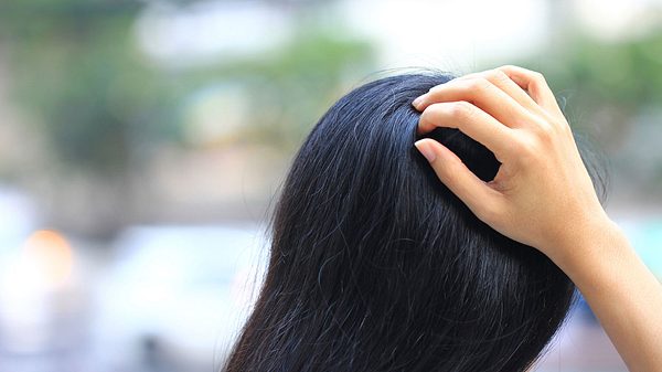 Eine dunkelhaarige Frau fasst sich in die Haare - Foto: iStock/MonthiraYodtiwong