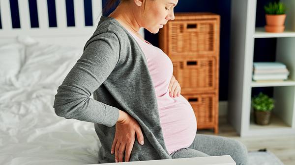 Eine Schwangere sitzt auf dem Bett - Foto: iStock/gpointstudio