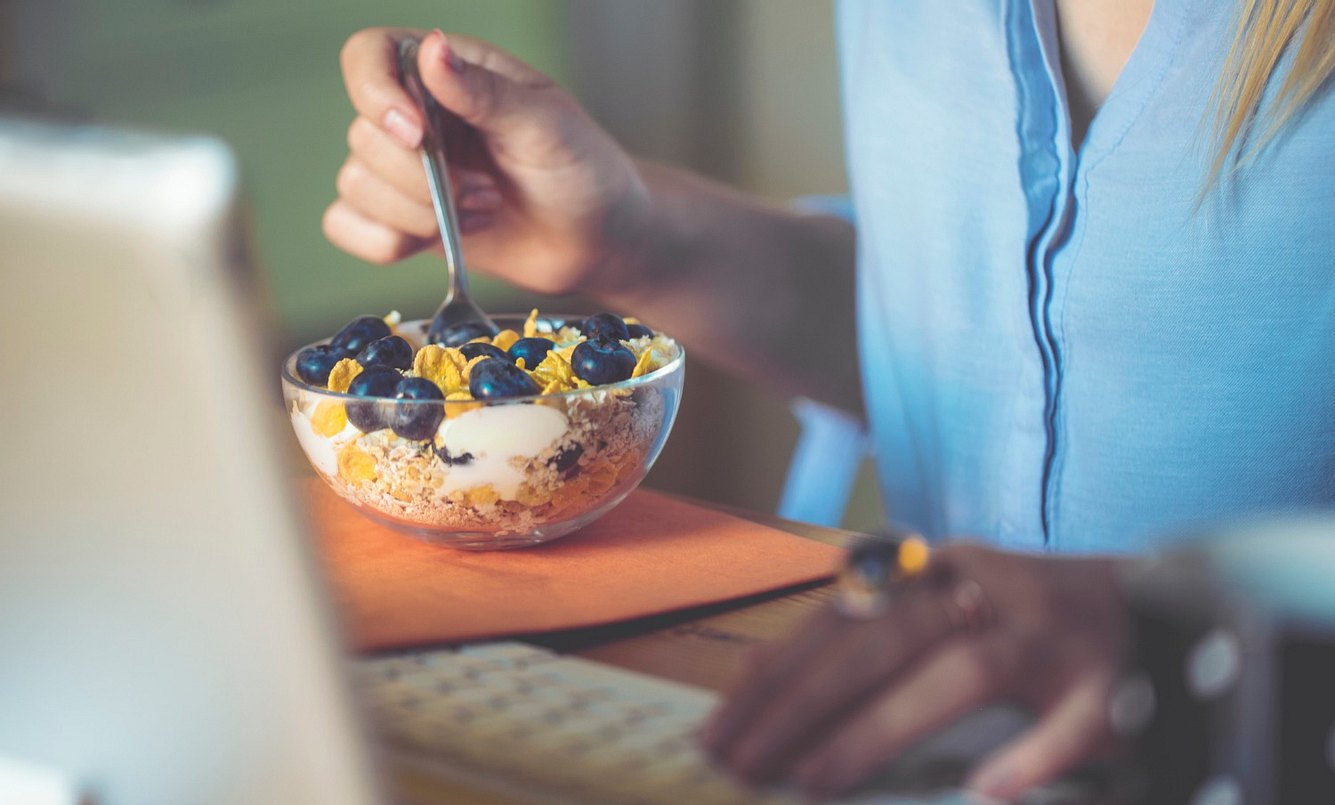 Frau isst Müsli mit Haferflocken und Früchten