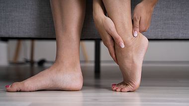 Frau fasst sich an schmerzenden Fuß - Foto: iStock/AndreyPopov