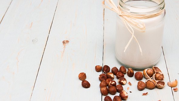 Glas mit Haselnussmilch und Haselnüssen - Foto: iStock/Andrew1Norton