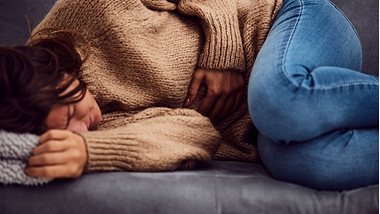 Frau hält sich den schmerzenden Bauch - Foto: istock/m-gucci