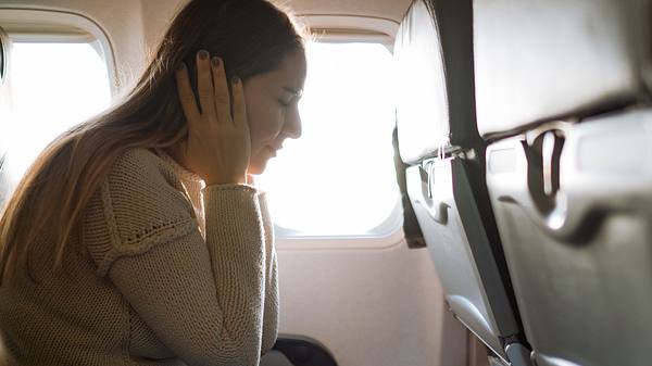 Eine Frau hat im Flugzeug einen Horsturz - Foto: iStock_ozgurcankaya