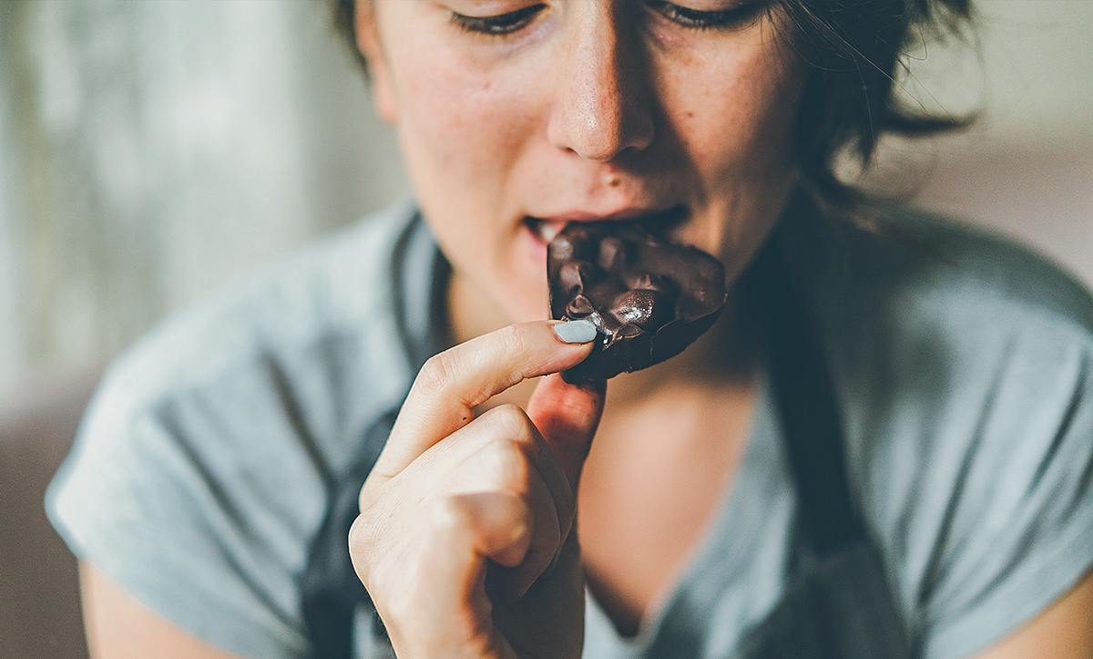 Eine Frau isst ein Stück Schokolade