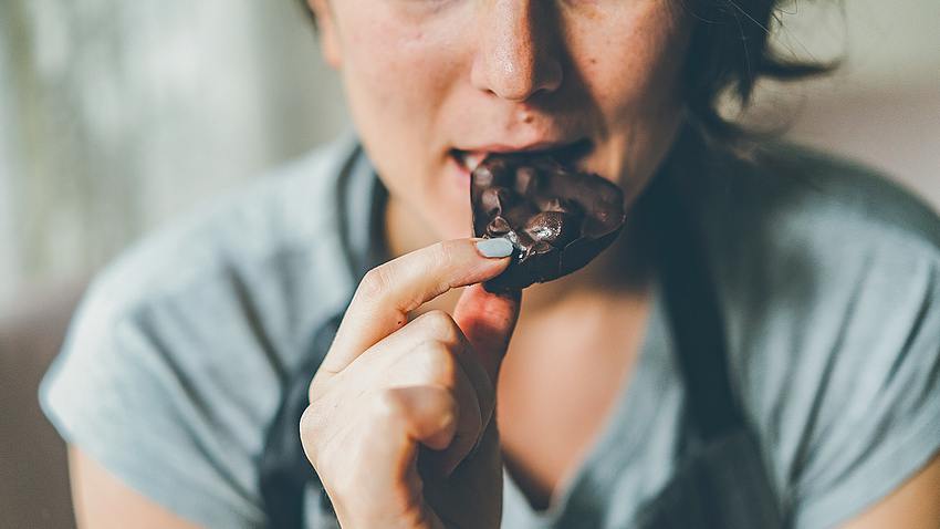 Eine Frau isst ein Stück Schokolade - Foto: istock_burakkarademir
