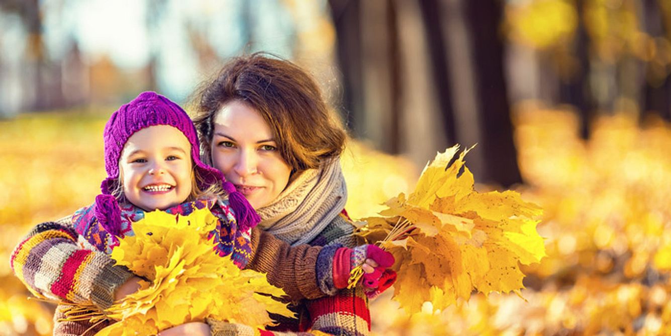 Mama mit Kind im Herbstlaub
