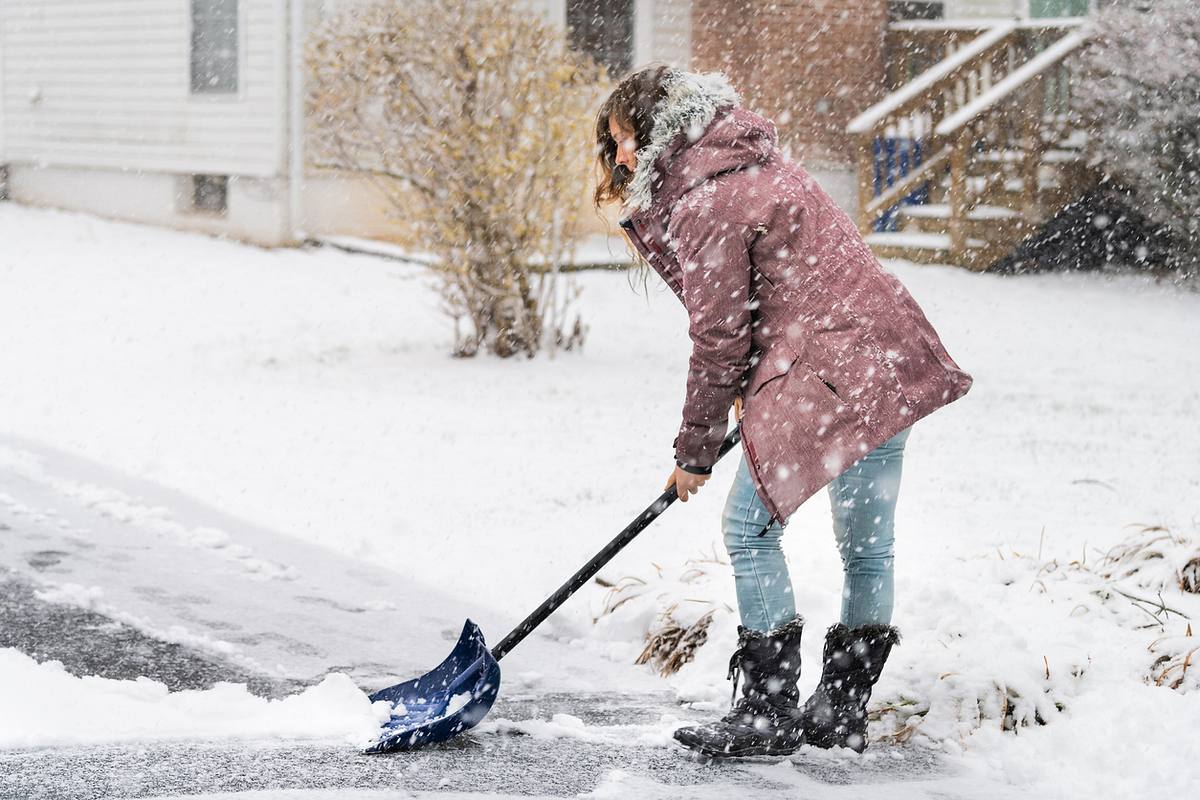 Frau beim Schneeschippen im Winter