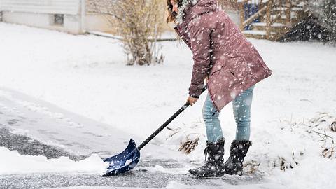 Frau beim Schneeschippen im Winter - Foto: iStock / ablokhin