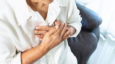 Eine ältere Frau fasst sich an den Brustkorb - Foto: iStock/PORNCHAI SODA