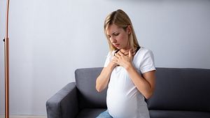 Schwangere Frau fasst sich an den Hals - Foto: iStock/AndreyPopov